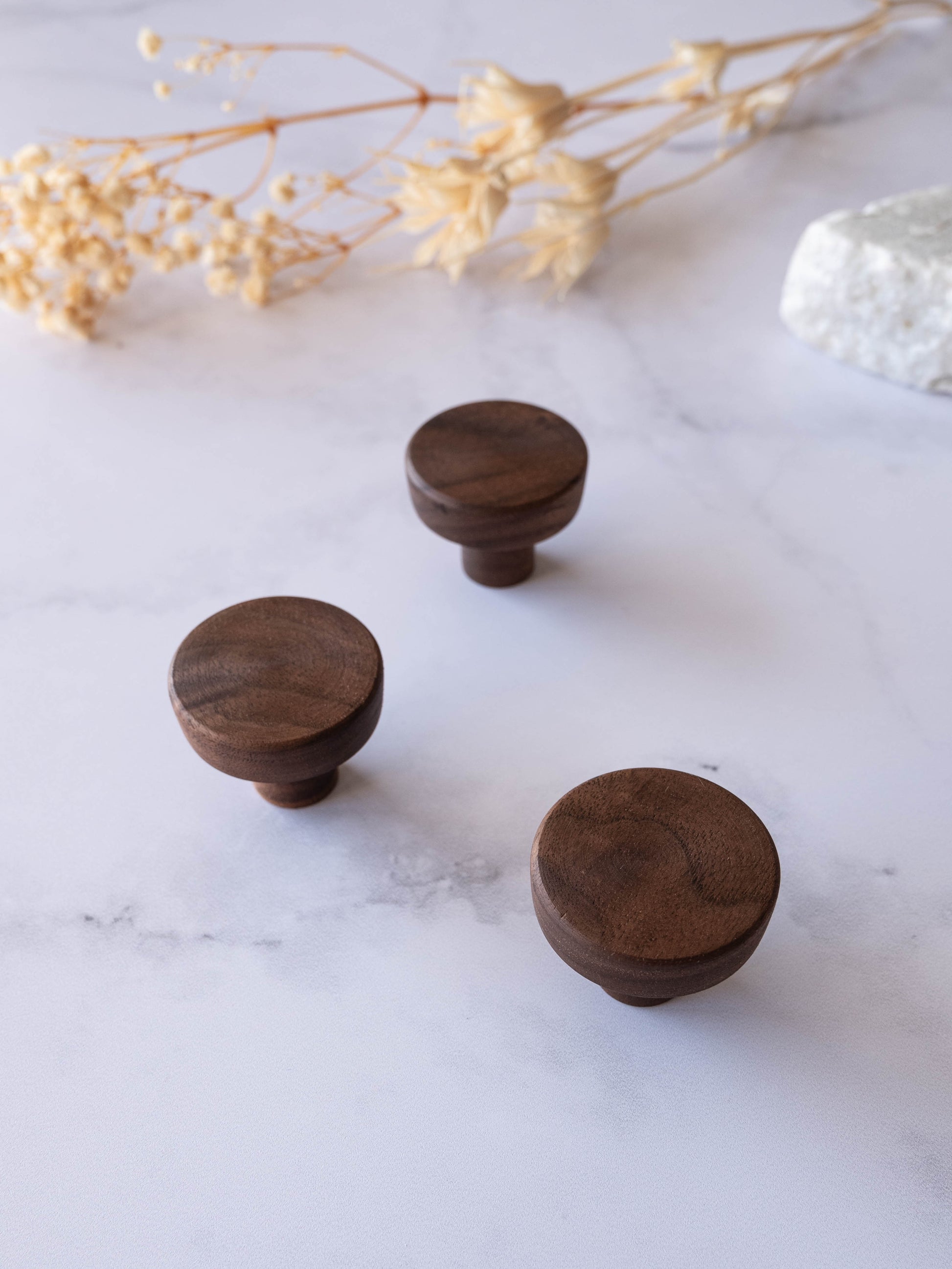 Boutons d’armoire en noyer naturel sur surface en marbre, poignées rondes minimalistes pour meubles.